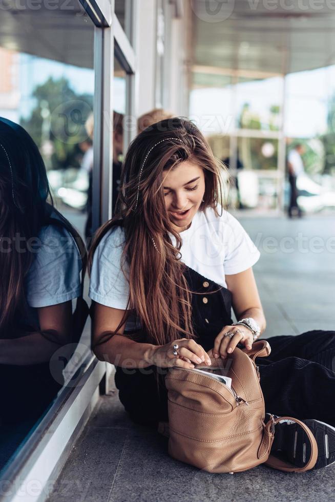 hermosa joven hipster está buscando algo en su bolso foto