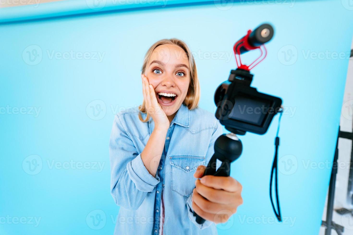 Beautiful girl blogger relieves itself at camera isolated blue background photo