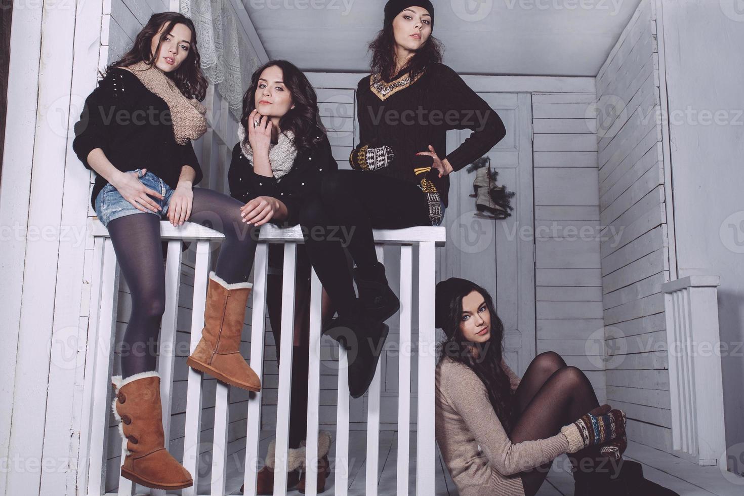 Four stylish models posing sitting on the fence. Christmas background photo