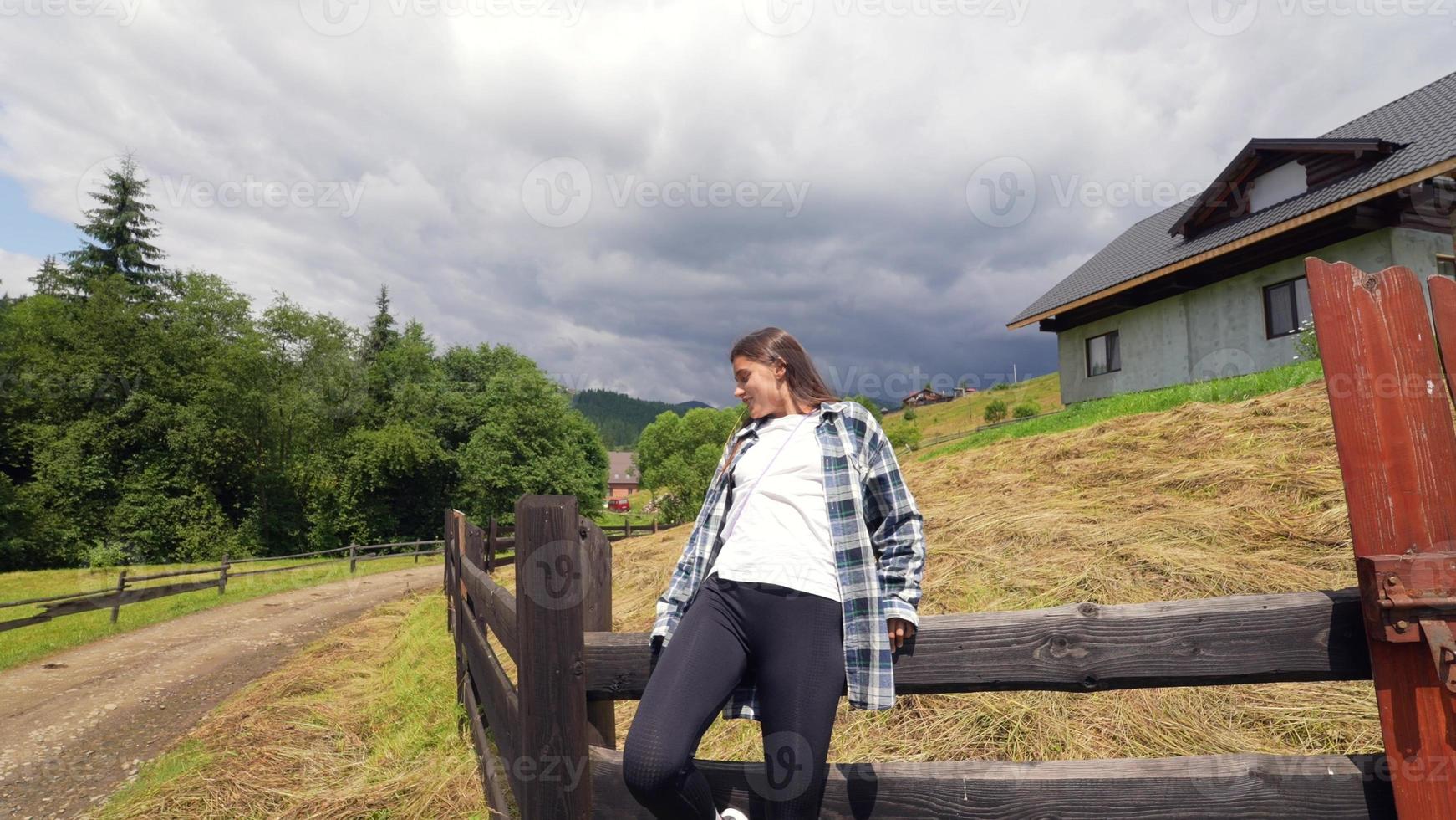 A young attractive Caucasian female sitting on a fence photo