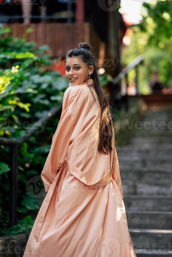 Young smiling woman on walking in the park wearing robe photo