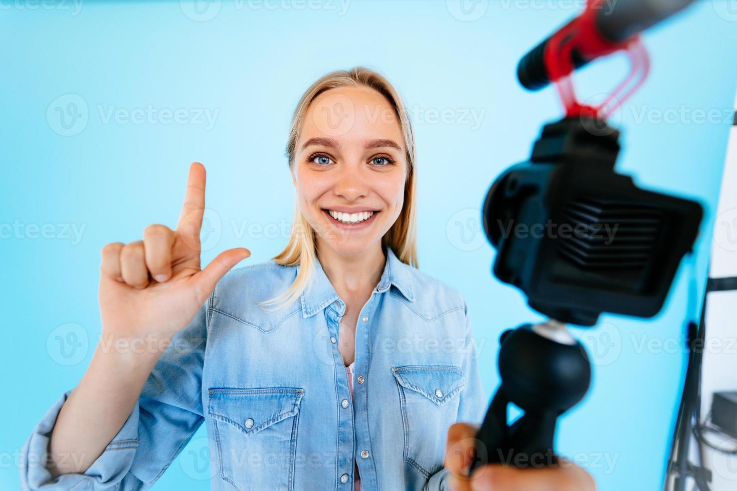 Beautiful girl blogger relieves itself at camera isolated blue background photo