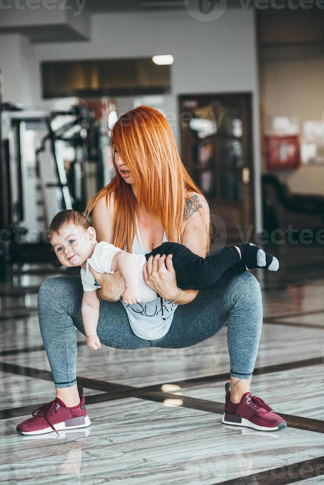 joven madre con su hijo pequeño en el gimnasio foto