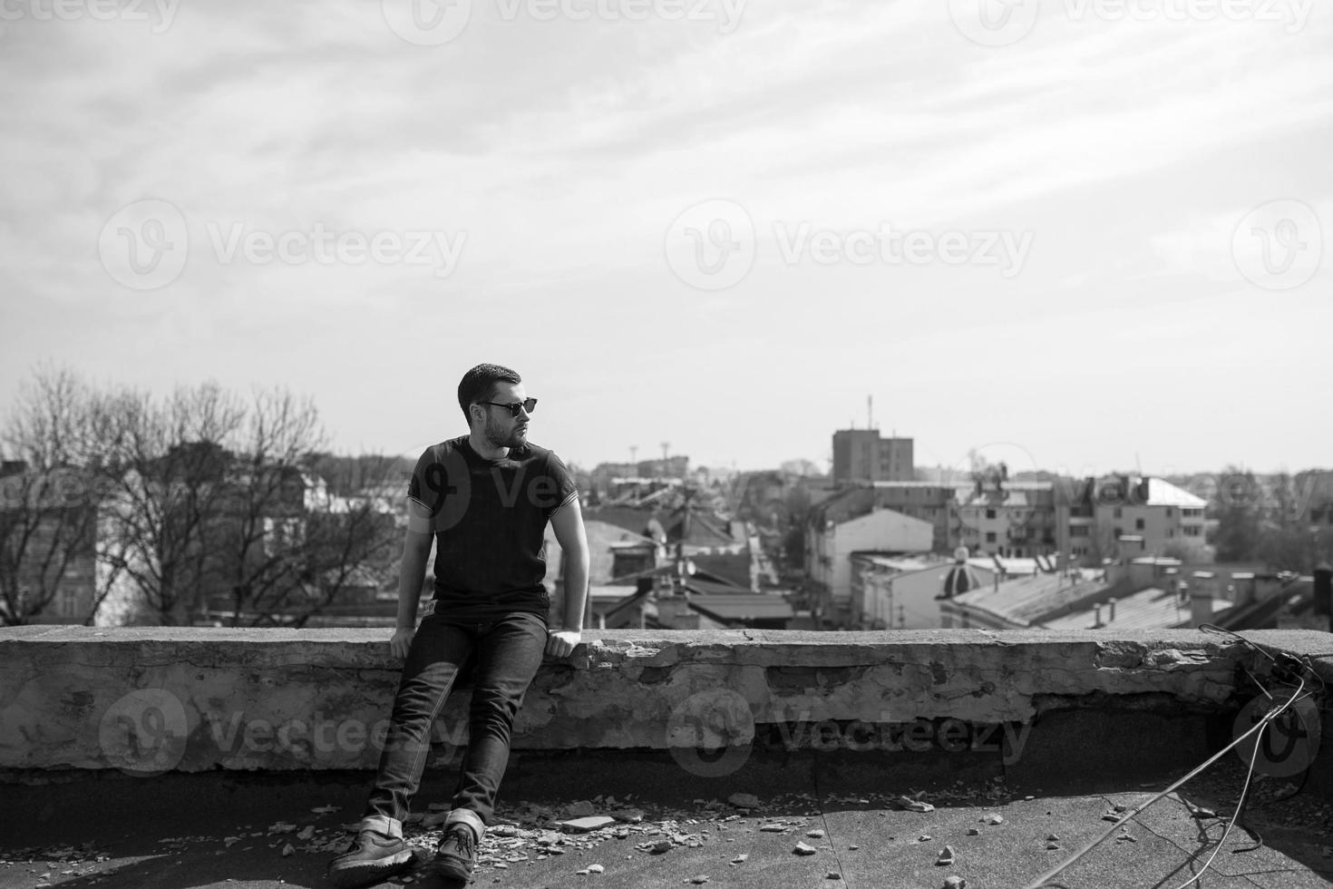 El hombre de las botas auténticas y el orillo de jeans en el techo del edificio en el casco antiguo foto