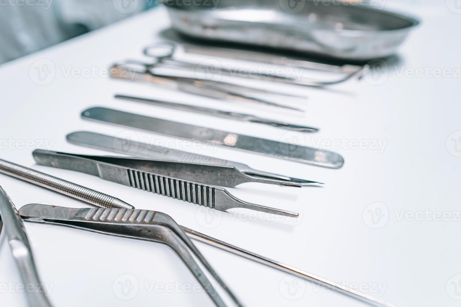 Several surgical instruments lie on a white table photo