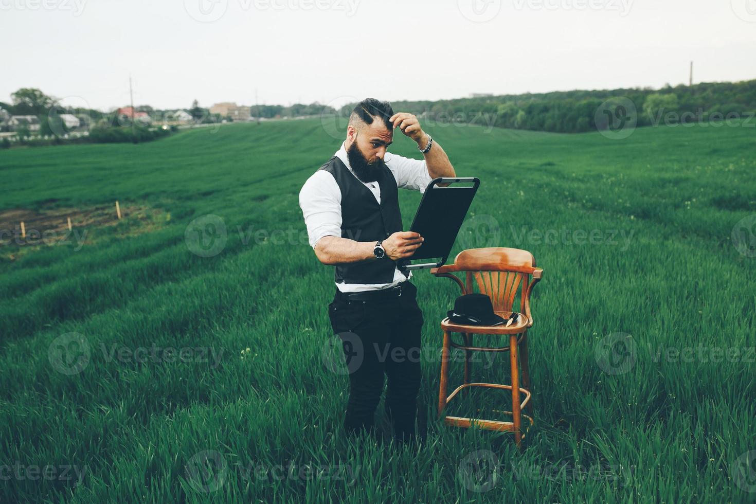 Bearded man carries a chair on the field photo