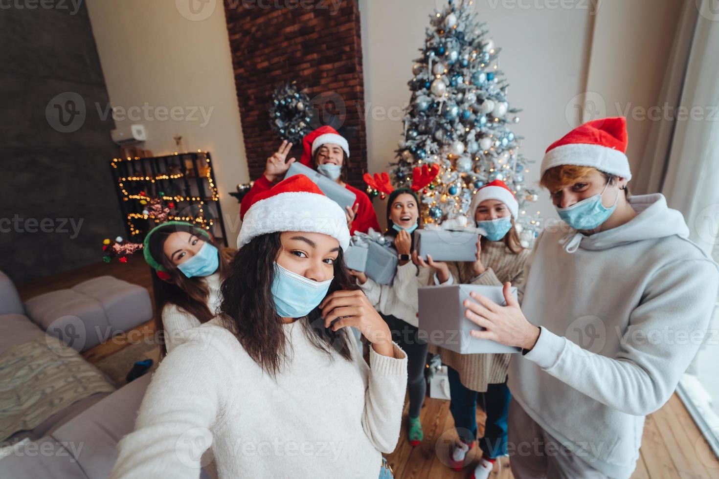 Multiethnic group of friends in Santa hats with gifts in hands. photo