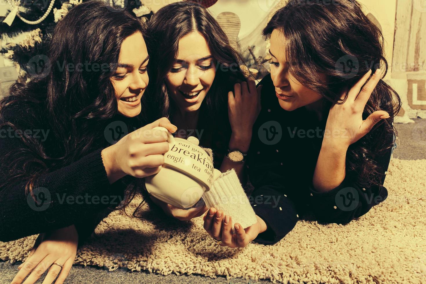 Beautiful girl eating Christmas cookies and drink tea while lying on a carpet. Decorative vintage apartment. photo
