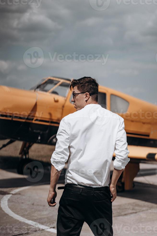 A man standing on the background of a small single engine plane. photo