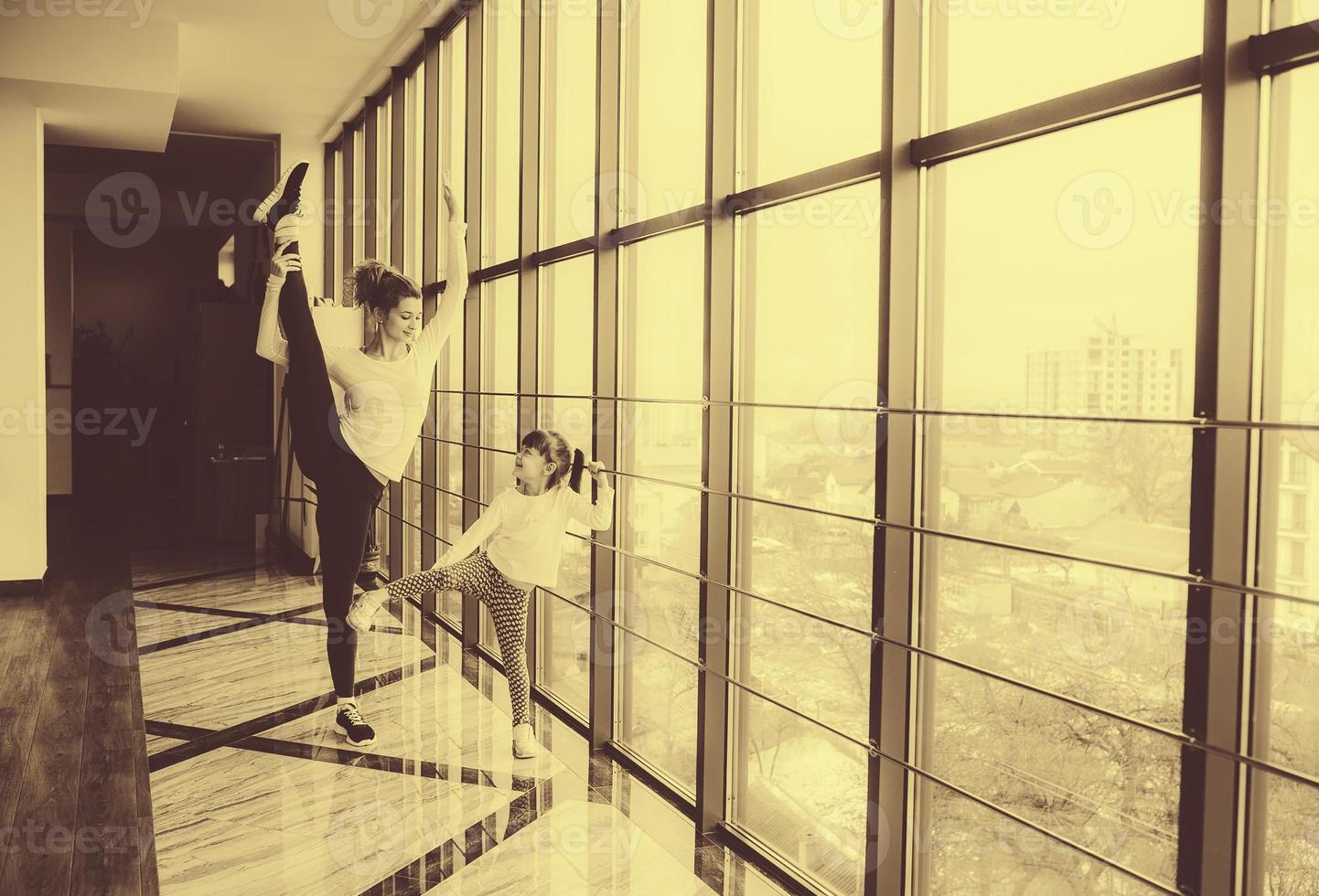 Mother learning daughter to make a high leg strech photo