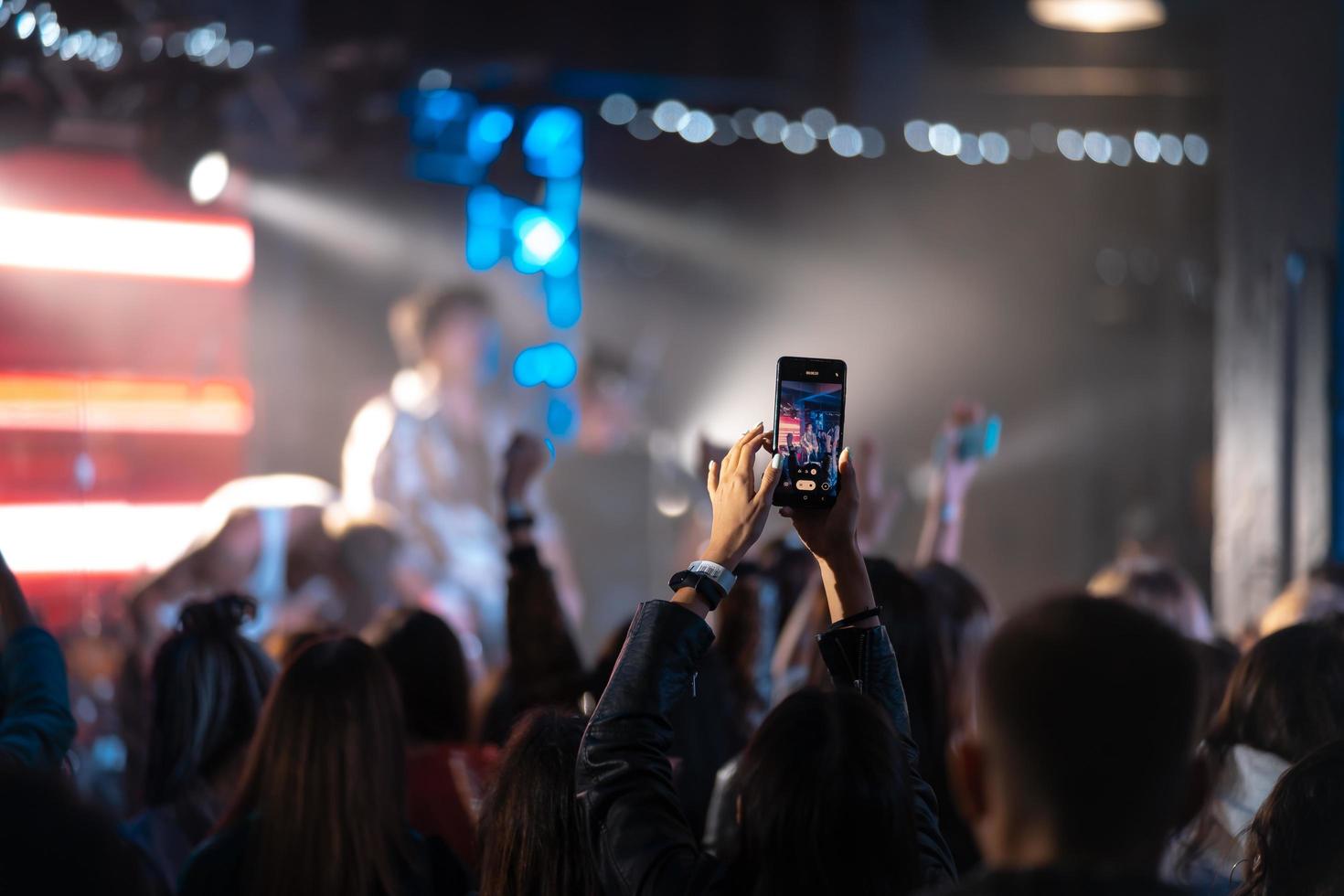 Person close up of recording video with smartphone during a concert. photo