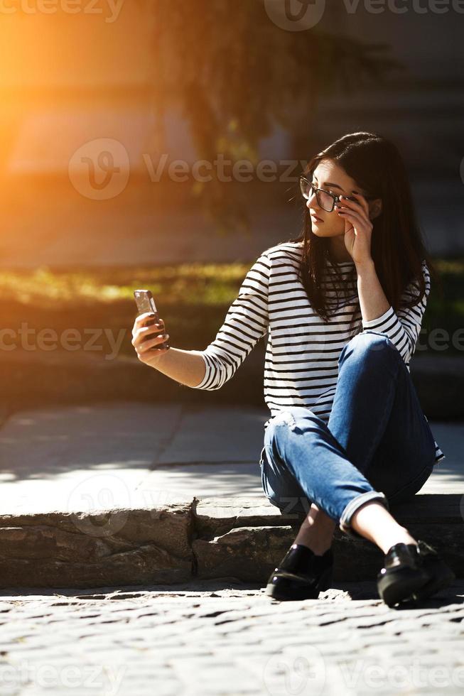 model in the middle of the city with phone photo