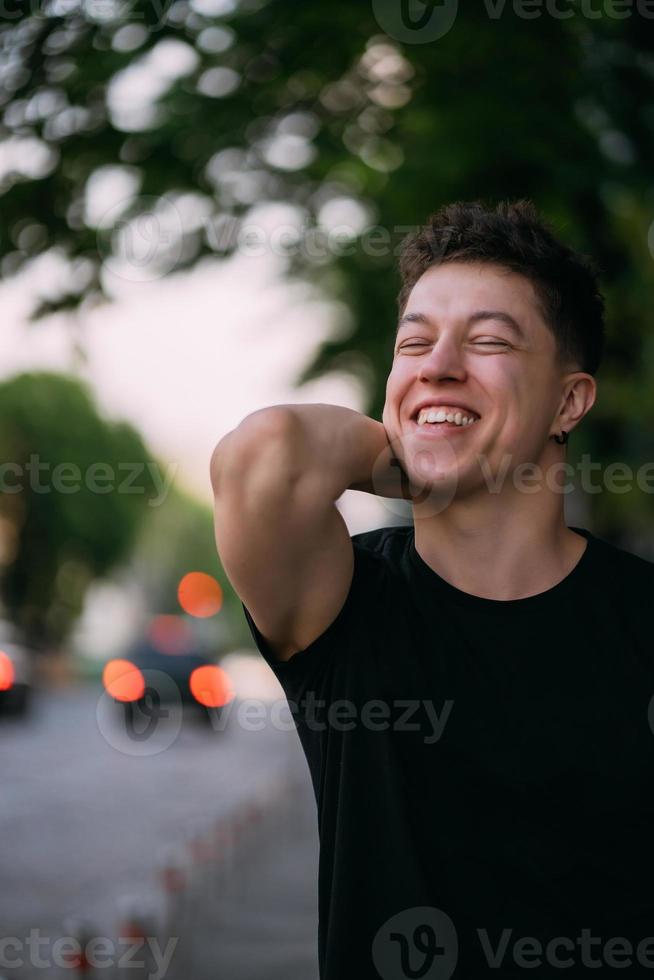 Young adult man in a black t-shirt and jeans walks on a city street photo