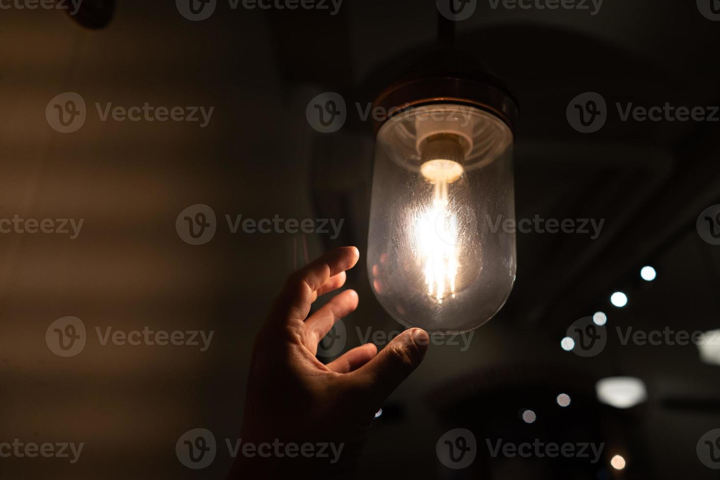 Hand reaching for a vintage light bulb. photo