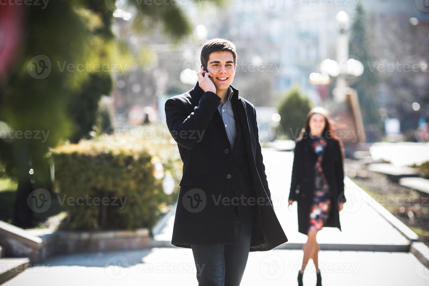 businessman talking on the phone while woman comes to him photo