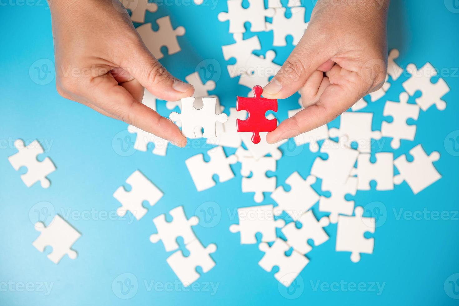 Close up hand holding and playing jigsaw game incomplete. White part of jigsaw puzzle pieces on blue background. concepts of problem solving, business, teamwork. photo