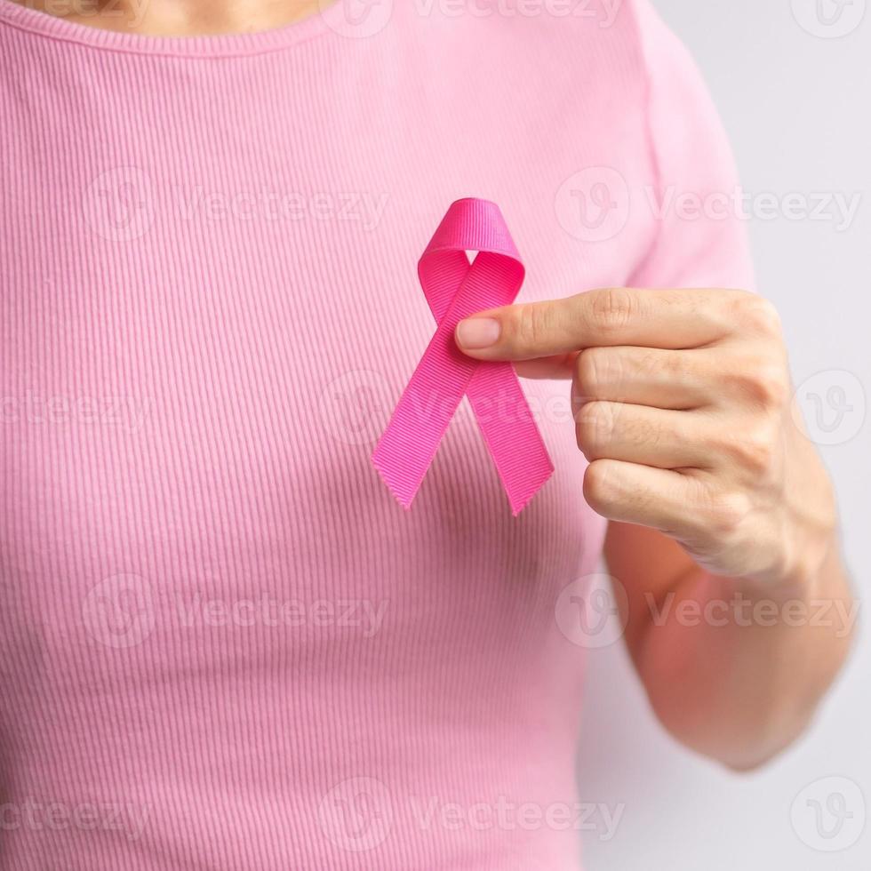 mes de concientización sobre el cáncer de mama de octubre rosa, la mano de la mujer sostiene una cinta rosa y usa una camisa para apoyar la vida y la enfermedad de las personas. concepto del mes nacional de los sobrevivientes del cáncer, la madre y el día mundial del cáncer foto