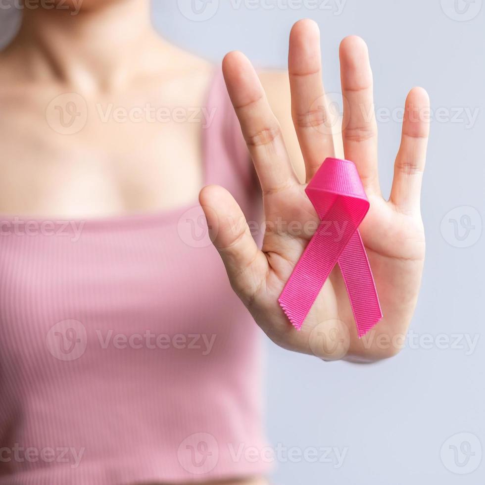 mes de concientización sobre el cáncer de mama de octubre rosa, la mano de la mujer sostiene una cinta rosa y usa una camisa para apoyar la vida y la enfermedad de las personas. concepto del mes nacional de los sobrevivientes del cáncer, la madre y el día mundial del cáncer foto