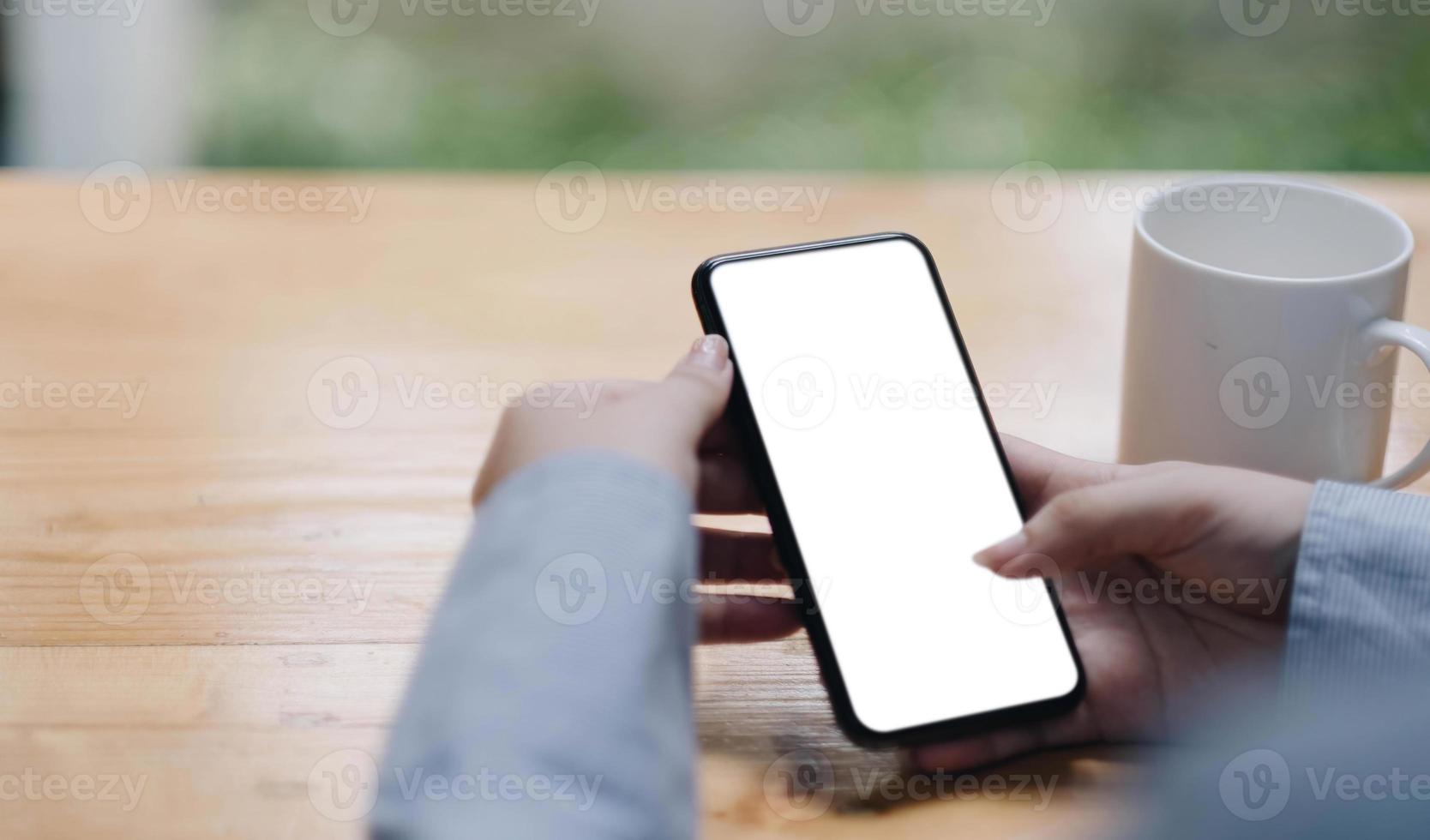 Cropped shot view of woman hands holding smart phone with blank copy space screen for your text message or information content, female reading text message on cell telephone during in urban setting. photo