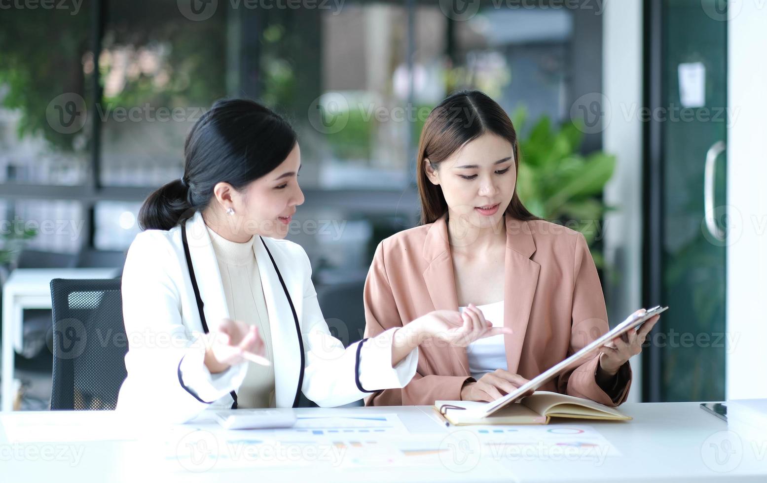 dos jóvenes empresarias asiáticas discuten el trabajo del proyecto de inversión y la estrategia de planificación. gente de negocios hablando junto con una computadora portátil en la oficina. foto