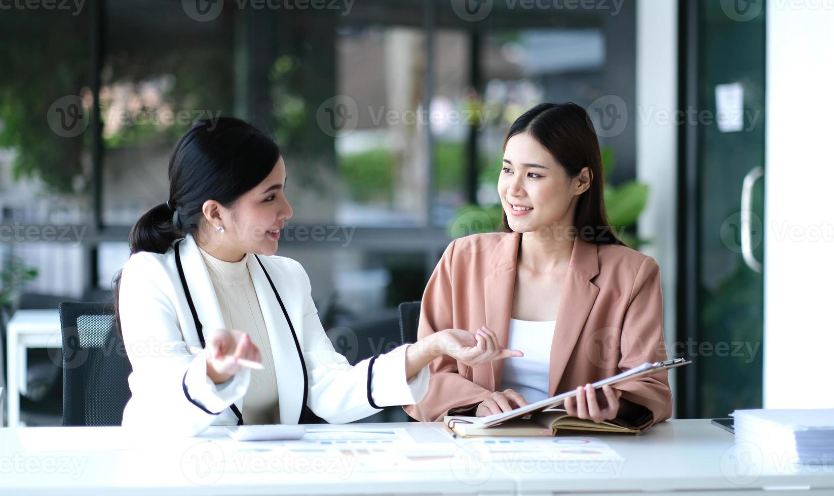 dos jóvenes empresarias asiáticas discuten el trabajo del proyecto de inversión y la estrategia de planificación. gente de negocios hablando junto con una computadora portátil en la oficina. foto