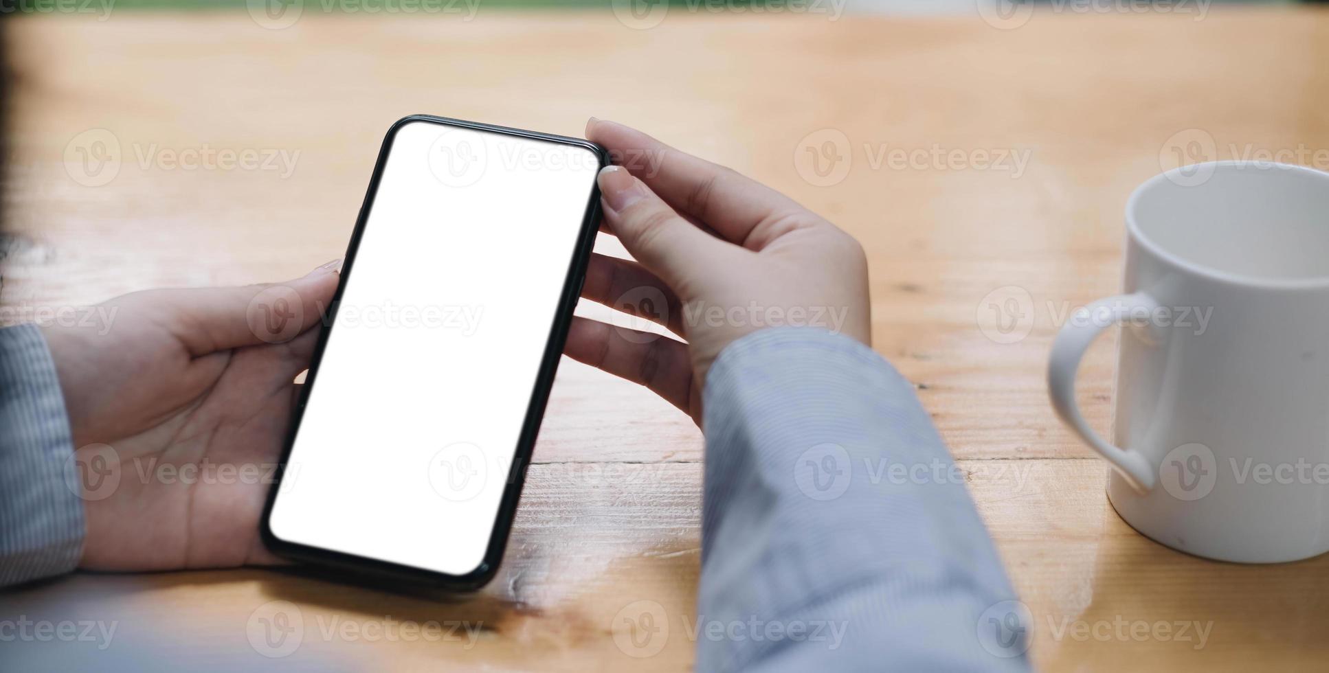 Cropped shot view of woman hands holding smart phone with blank copy space screen for your text message or information content, female reading text message on cell telephone during in urban setting. photo