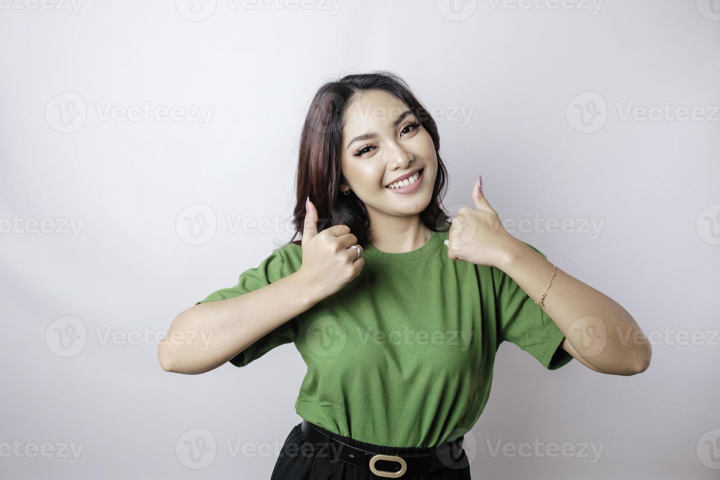 Excited Asian woman gives thumbs up hand gesture of approval, isolated by white background photo