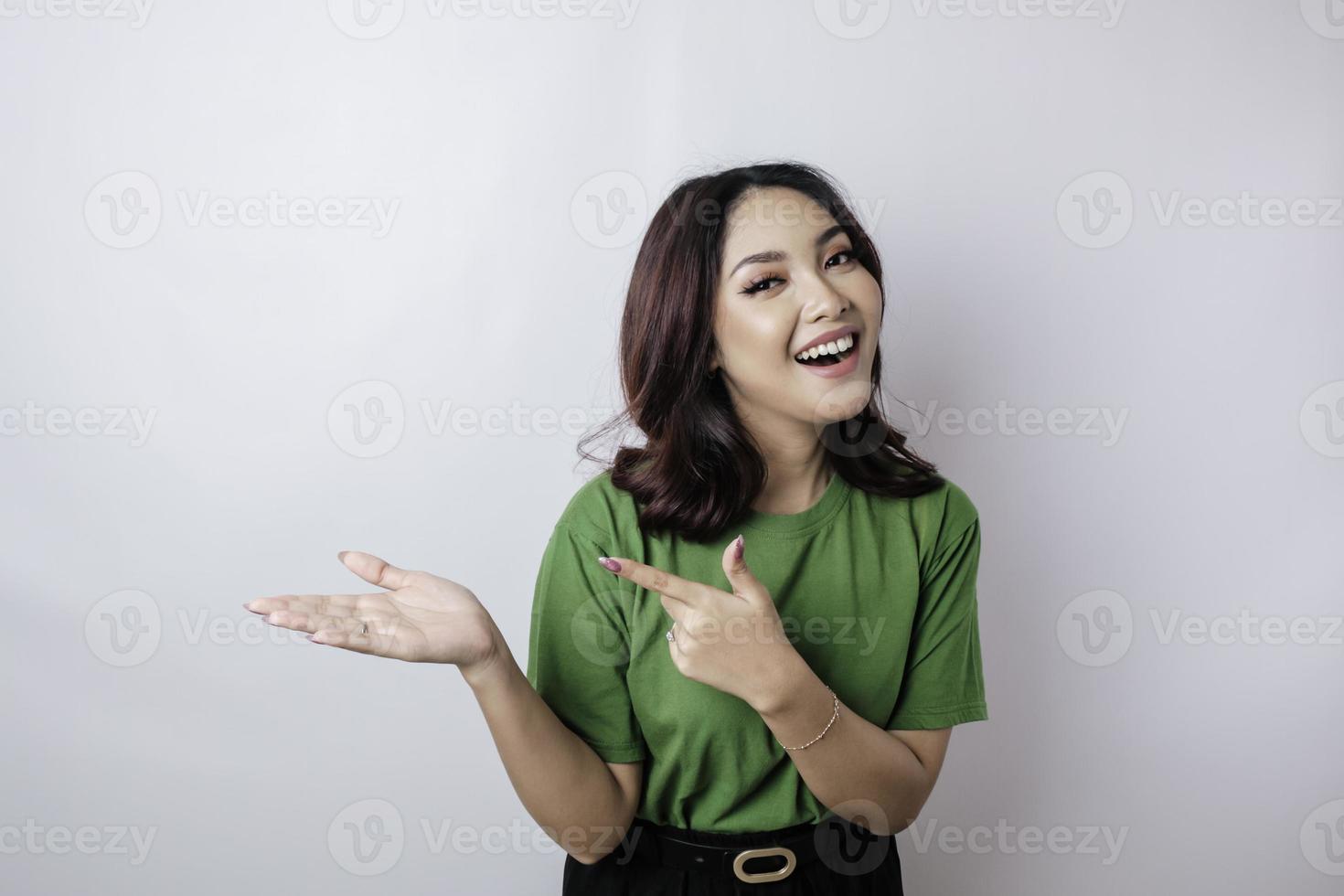 Smiling beautiful Asian woman pointing finger sideward to empty space isolated white background photo