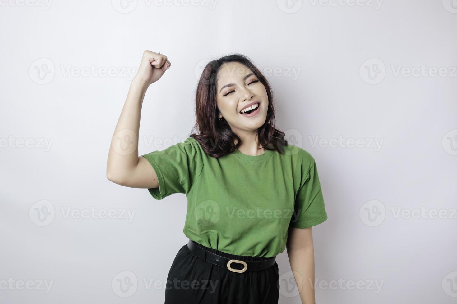 A young Asian woman with a happy successful expression wearing green shirt isolated by white background photo
