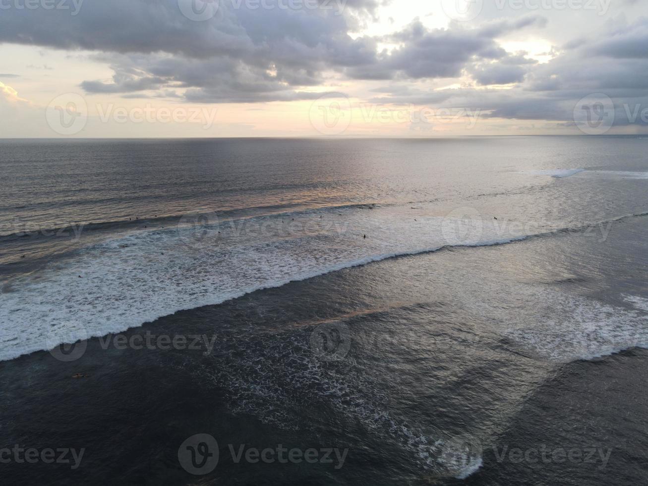 Aerial view of people surfing on waves with surfboards when vacation in Bali, Indonesia photo