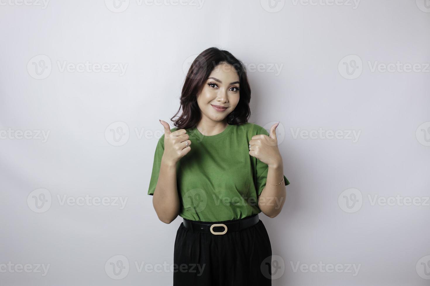 Excited Asian woman gives thumbs up hand gesture of approval, isolated by white background photo