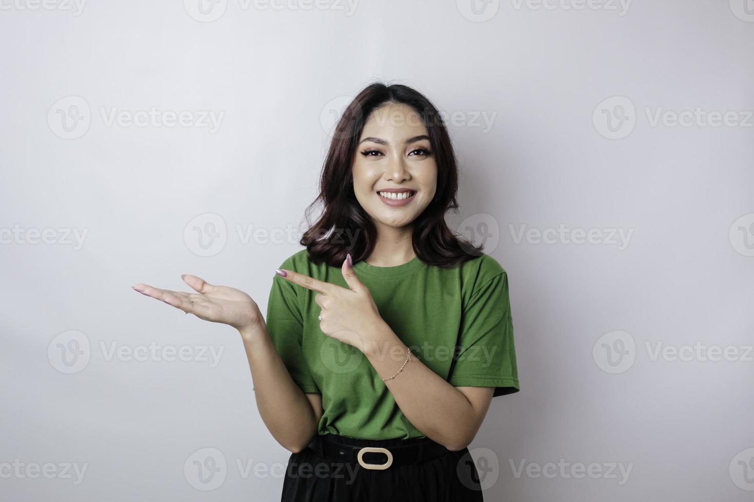 Smiling beautiful Asian woman pointing finger sideward to empty space isolated white background photo