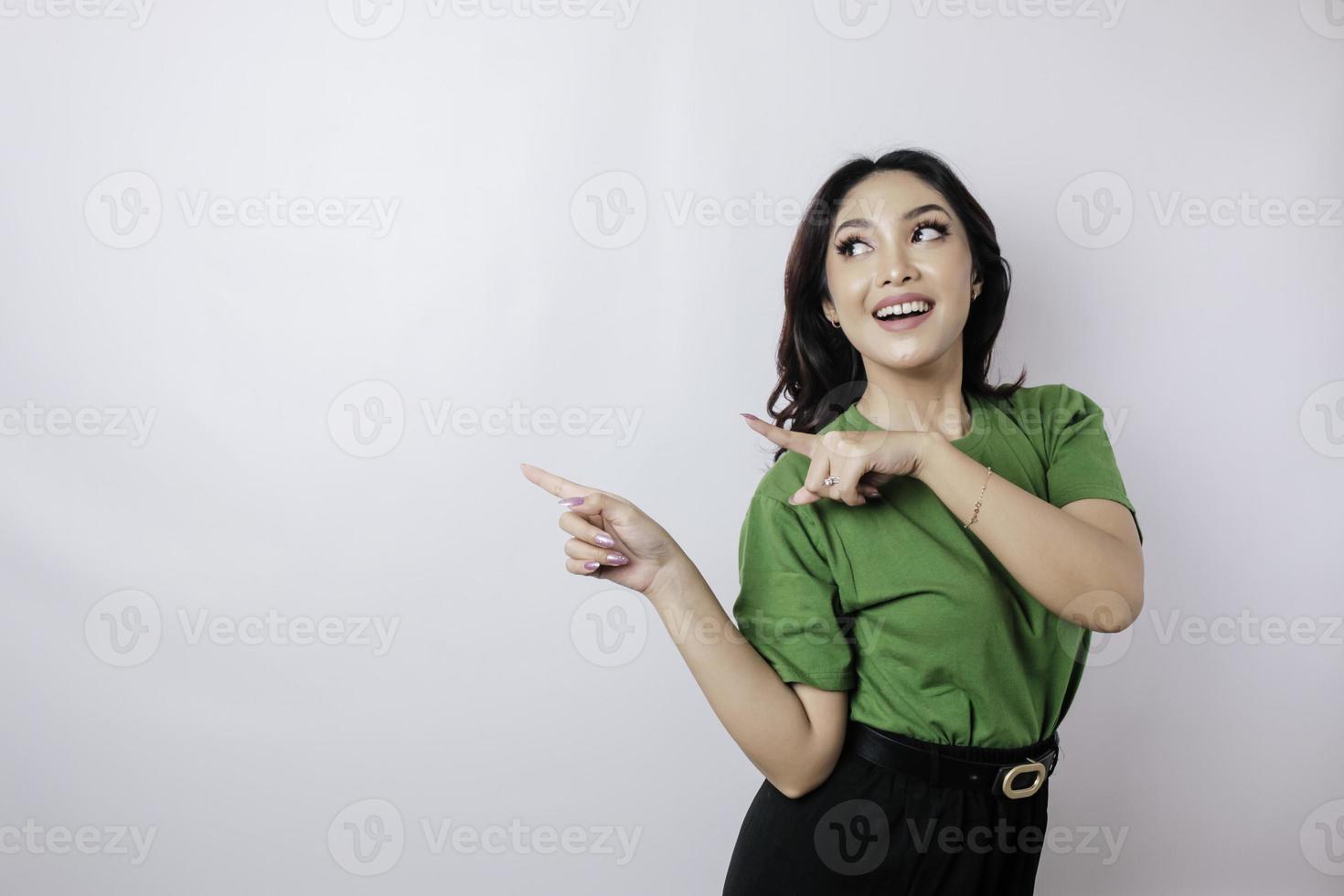 sonriente hermosa mujer asiática señalando con el dedo hacia un lado al espacio vacío aislado fondo blanco foto