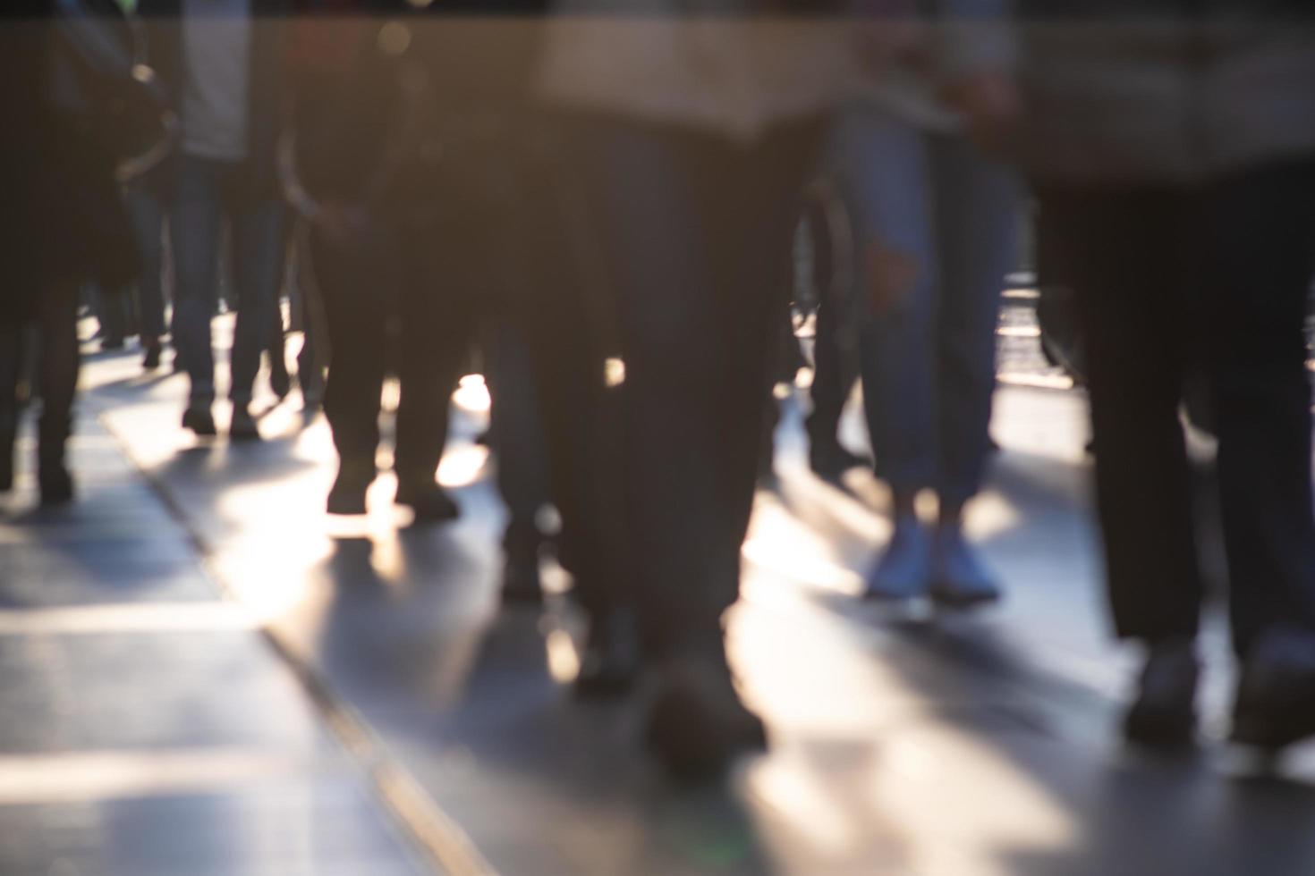 Legs of out of focus crowds walking on city sidewalks photo