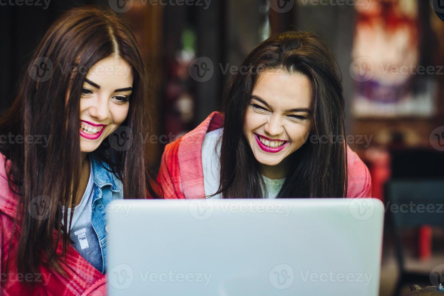 two girls watching something in laptop photo