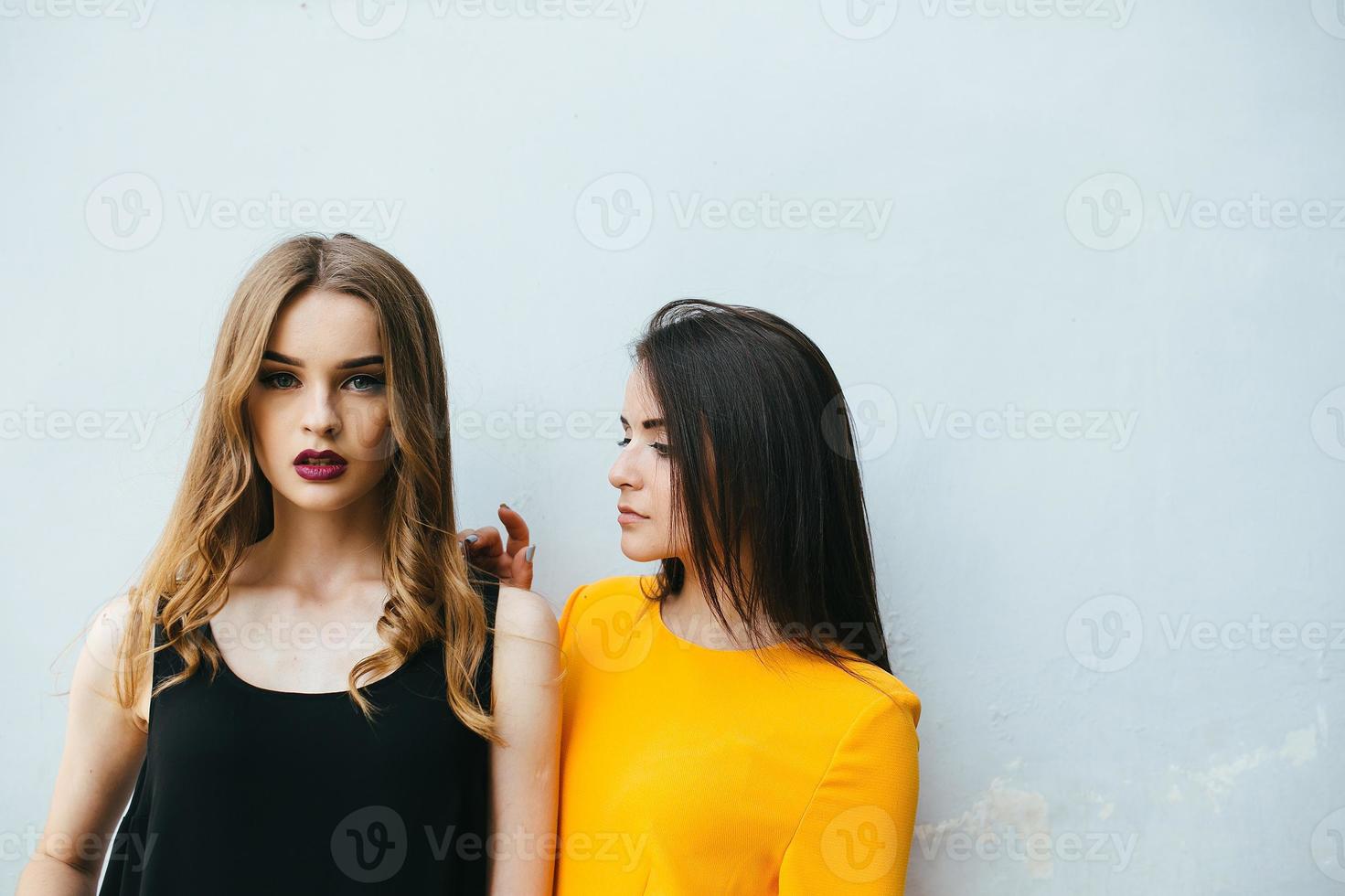 Two beautiful friends pose on white background photo