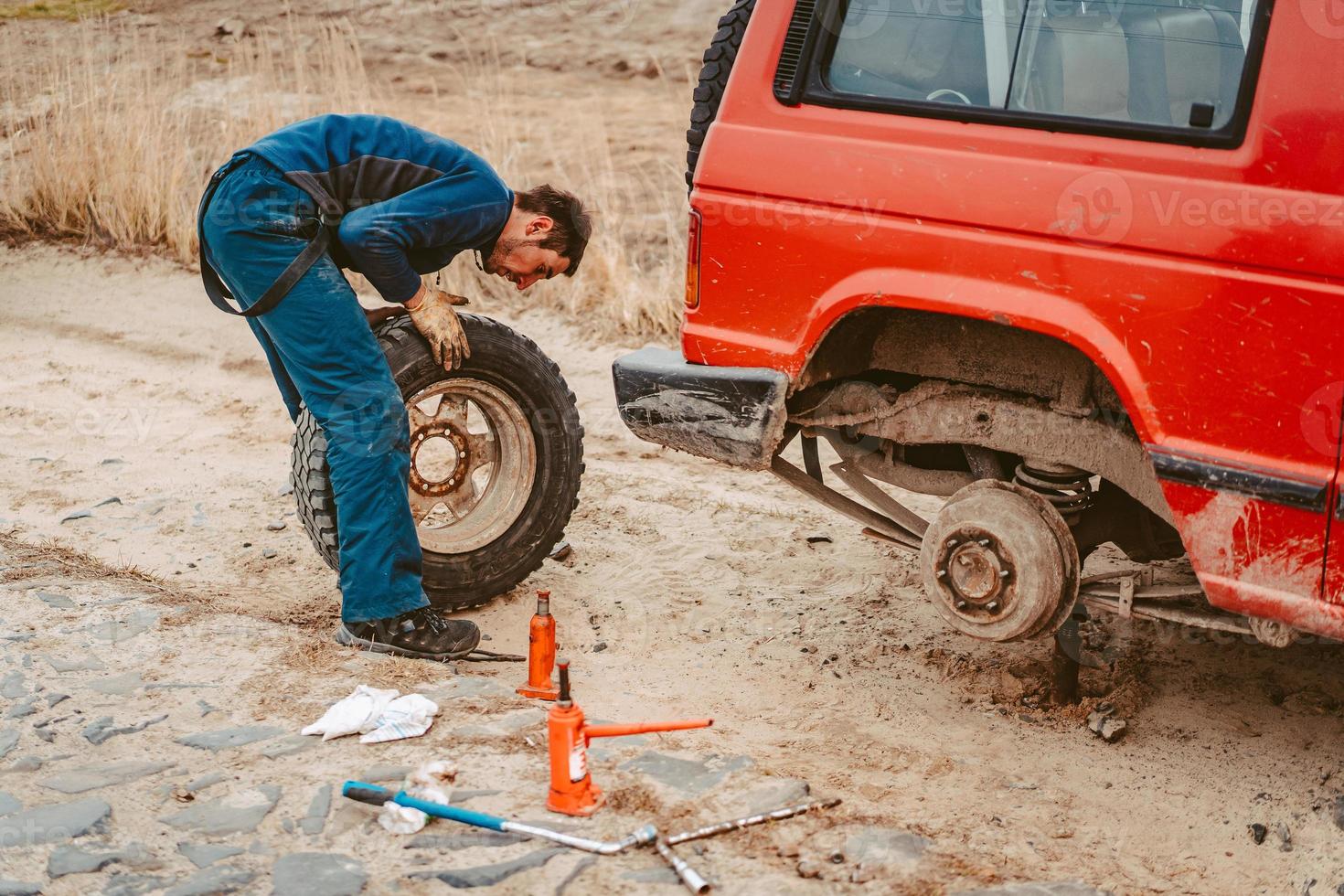 el hombre cambia la rueda manualmente en un camión todoterreno 4x4 foto