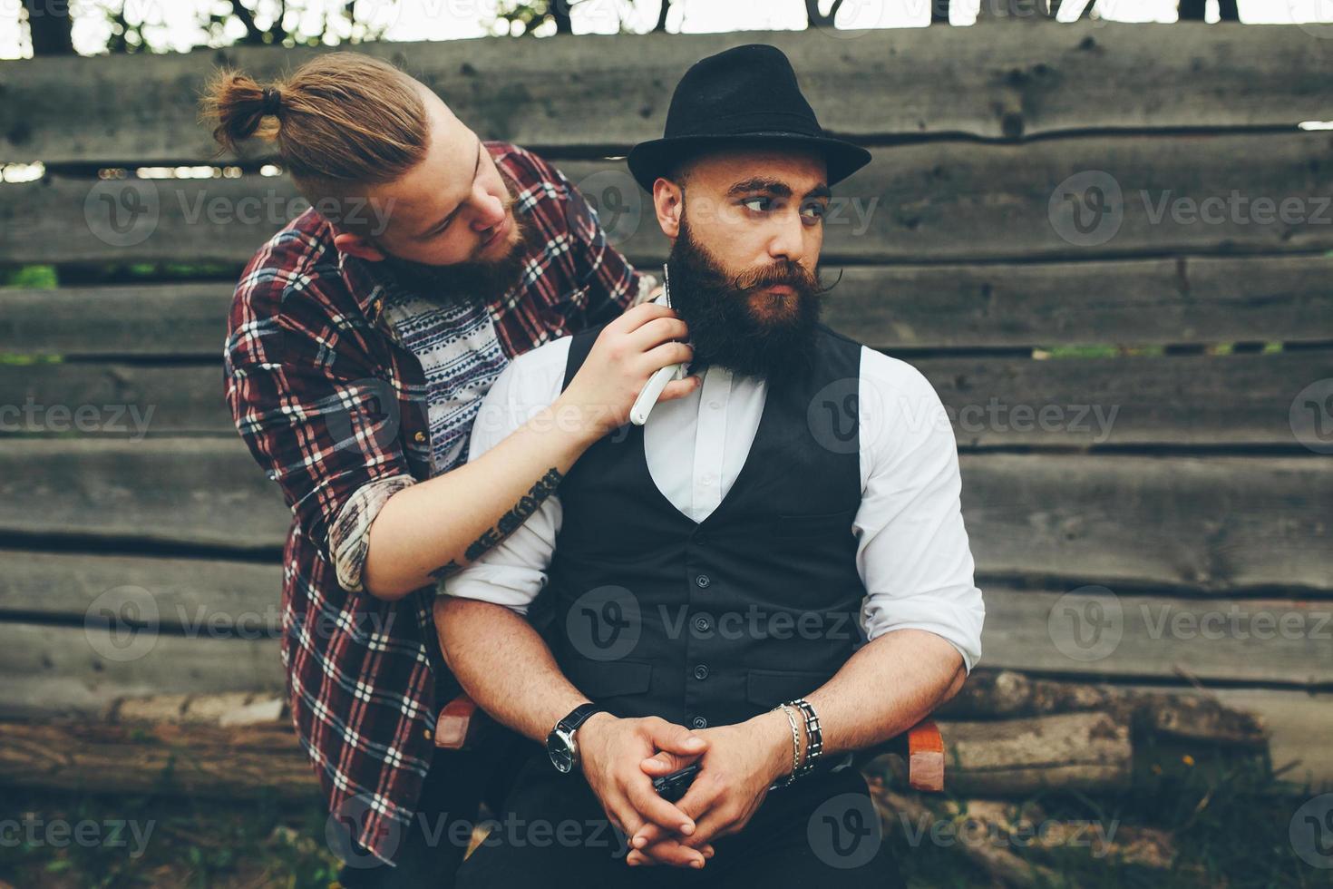 barbero afeita a un hombre barbudo foto