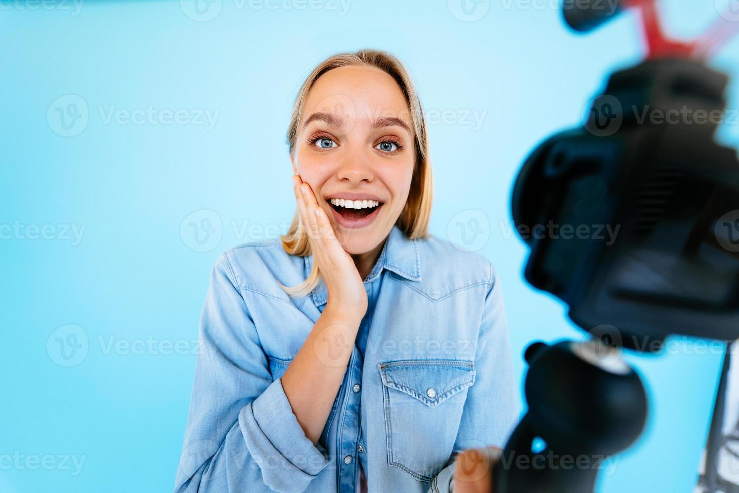 Beautiful girl blogger relieves itself at camera isolated blue background photo
