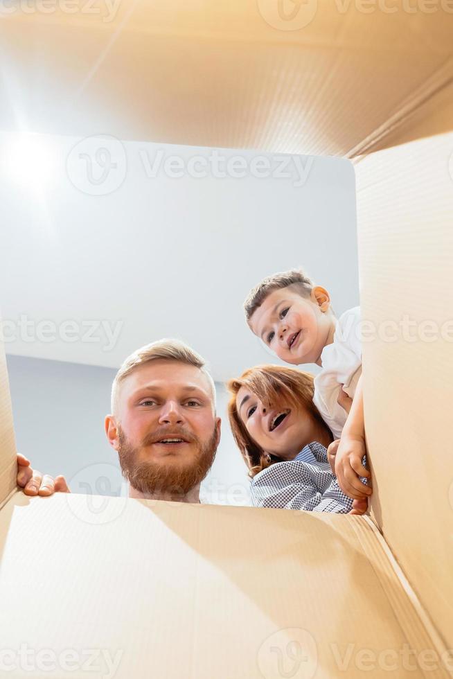 familia feliz recién mudada a una casa nueva y mirando la caja foto