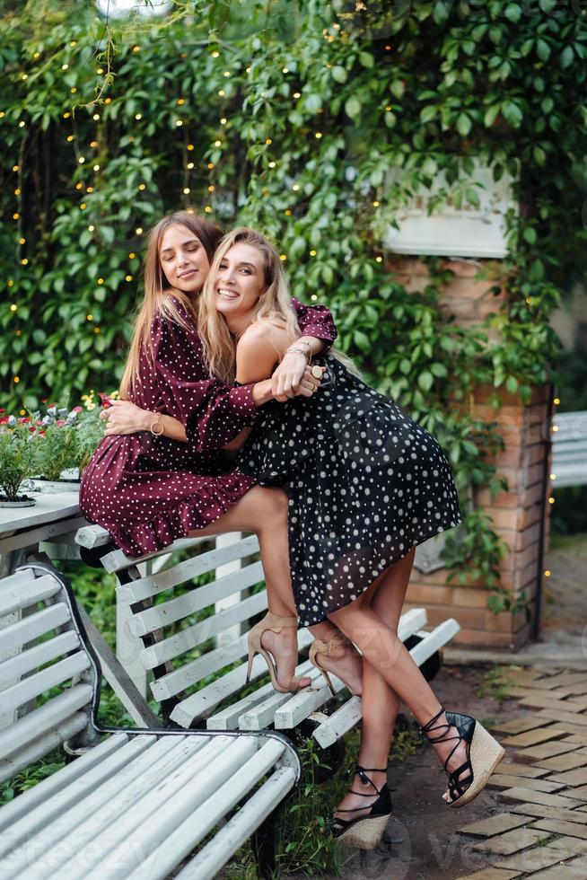 dos chicas en el parque abrazándose en el banco foto