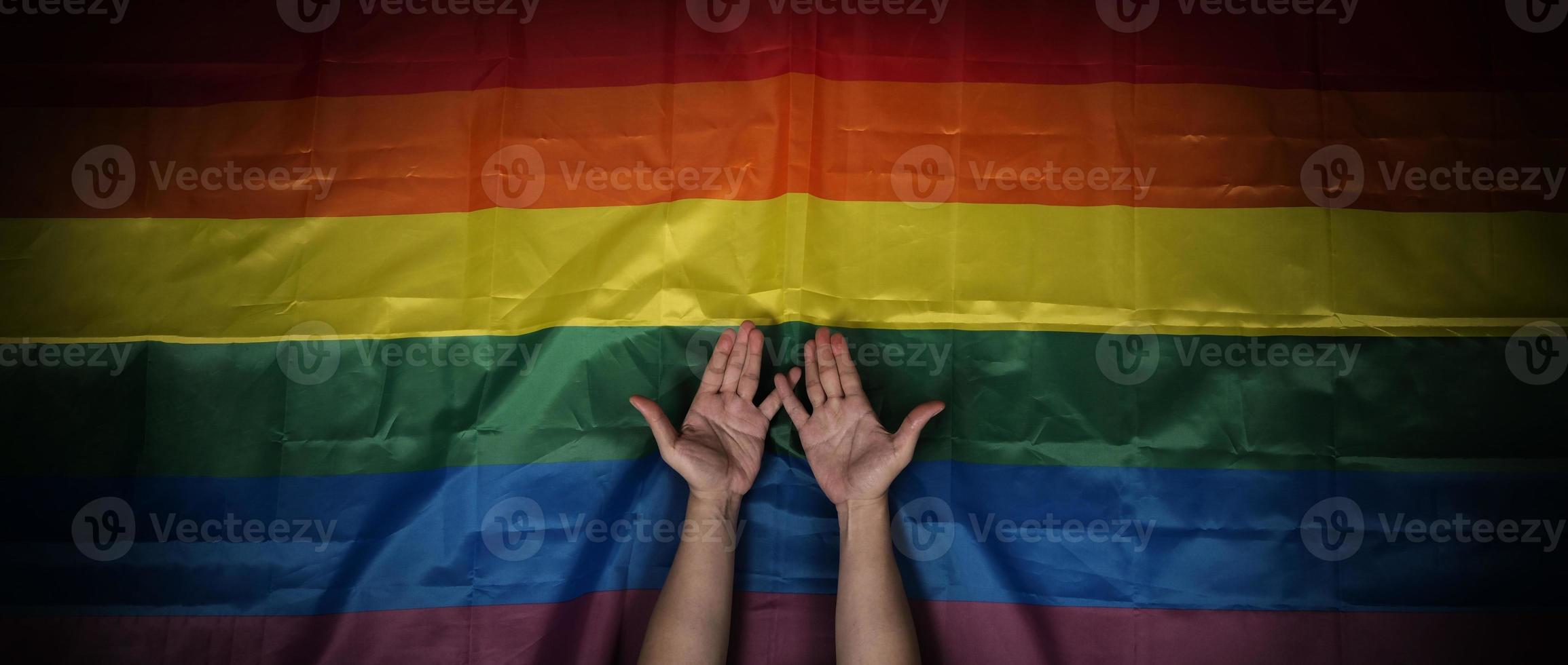 LGBTQ pride flag on black background. Lgbt rainbow flag in gay hand. photo