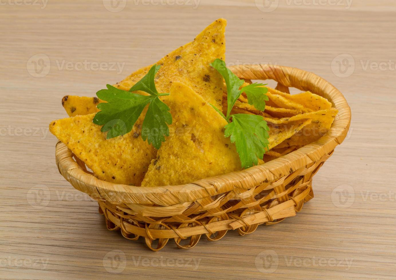 nachos en una canasta sobre fondo de madera foto