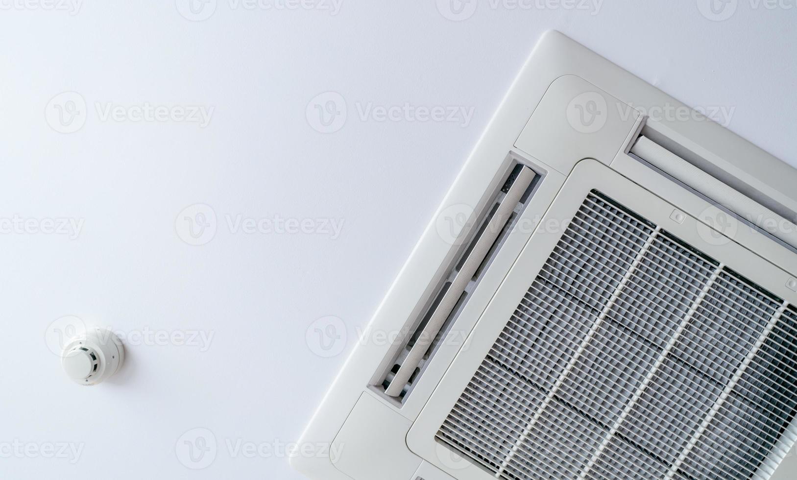 Cassette type air conditioner and smoke detector mounted on ceiling wall. Air duct on ceiling in hotel. Air heading unit on gypsum wall. Cool system in the building. Air flow and ventilation system. photo