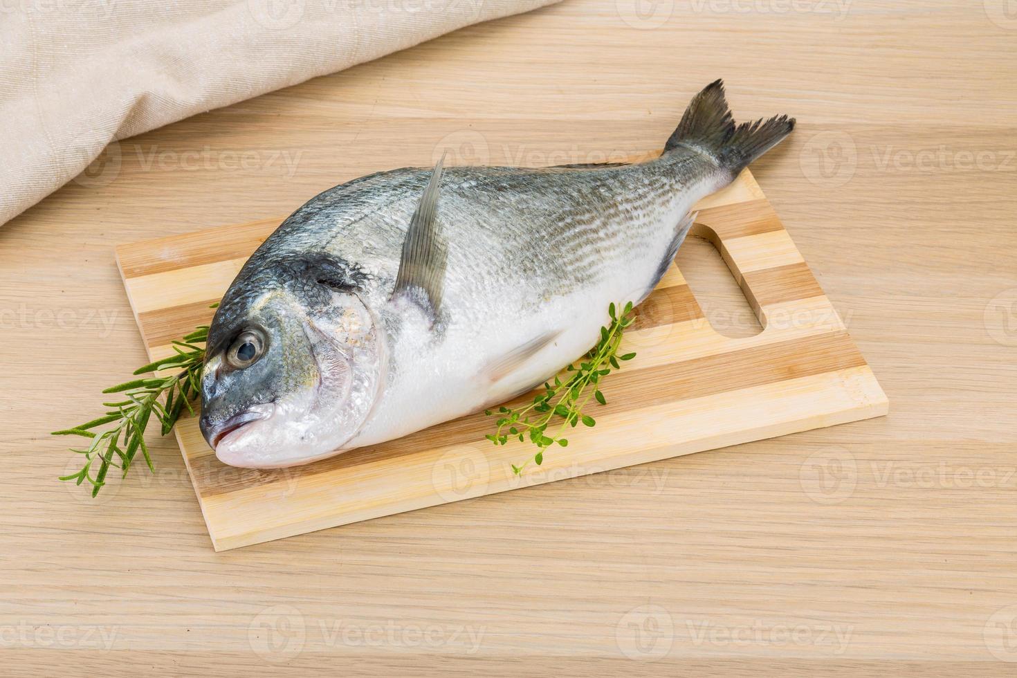 Raw dorado on wooden board and wooden background photo