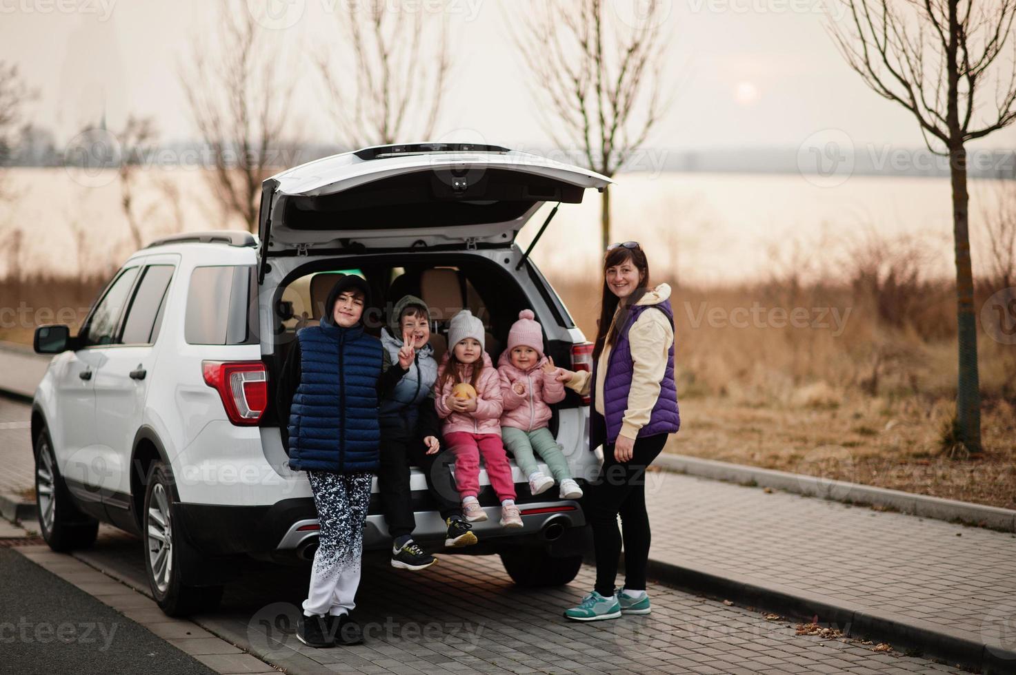 madre con cuatro hijos sentados en el maletero de un gran camión todoterreno. foto