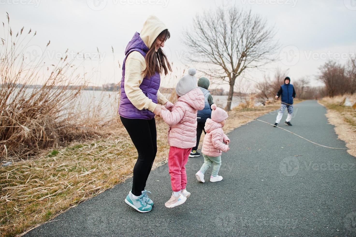 Mother with kids jump and having fun on the path by the lake. photo