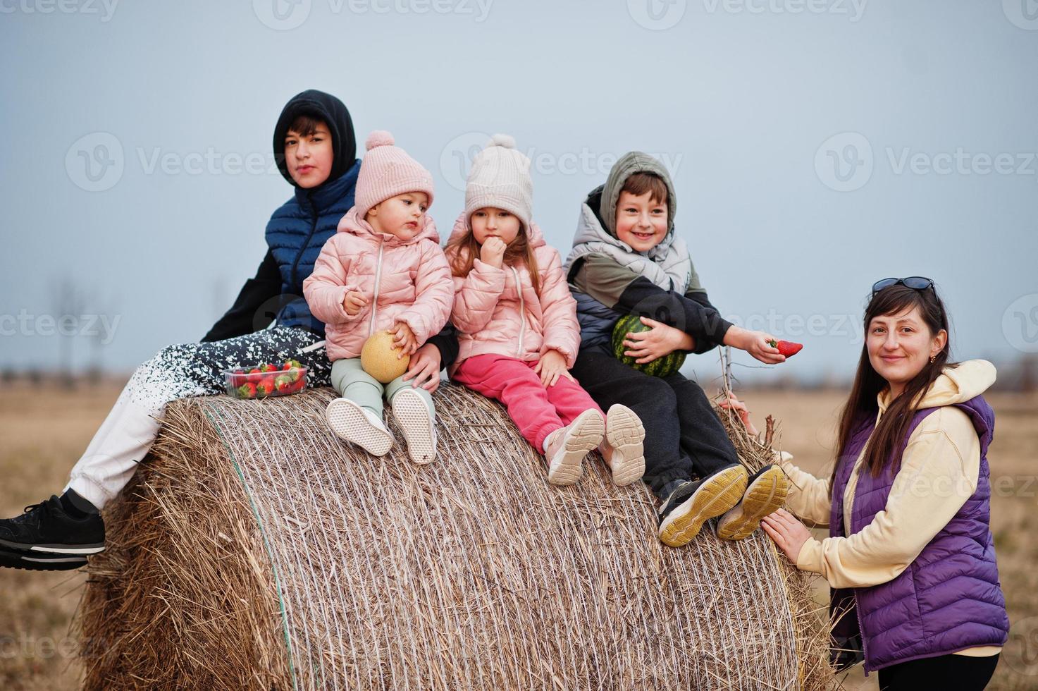 cuatro niños con madre divirtiéndose en haycock en el campo. foto