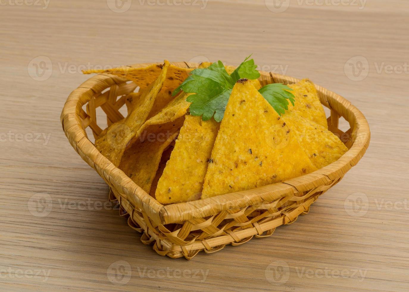 nachos en una canasta sobre fondo de madera foto