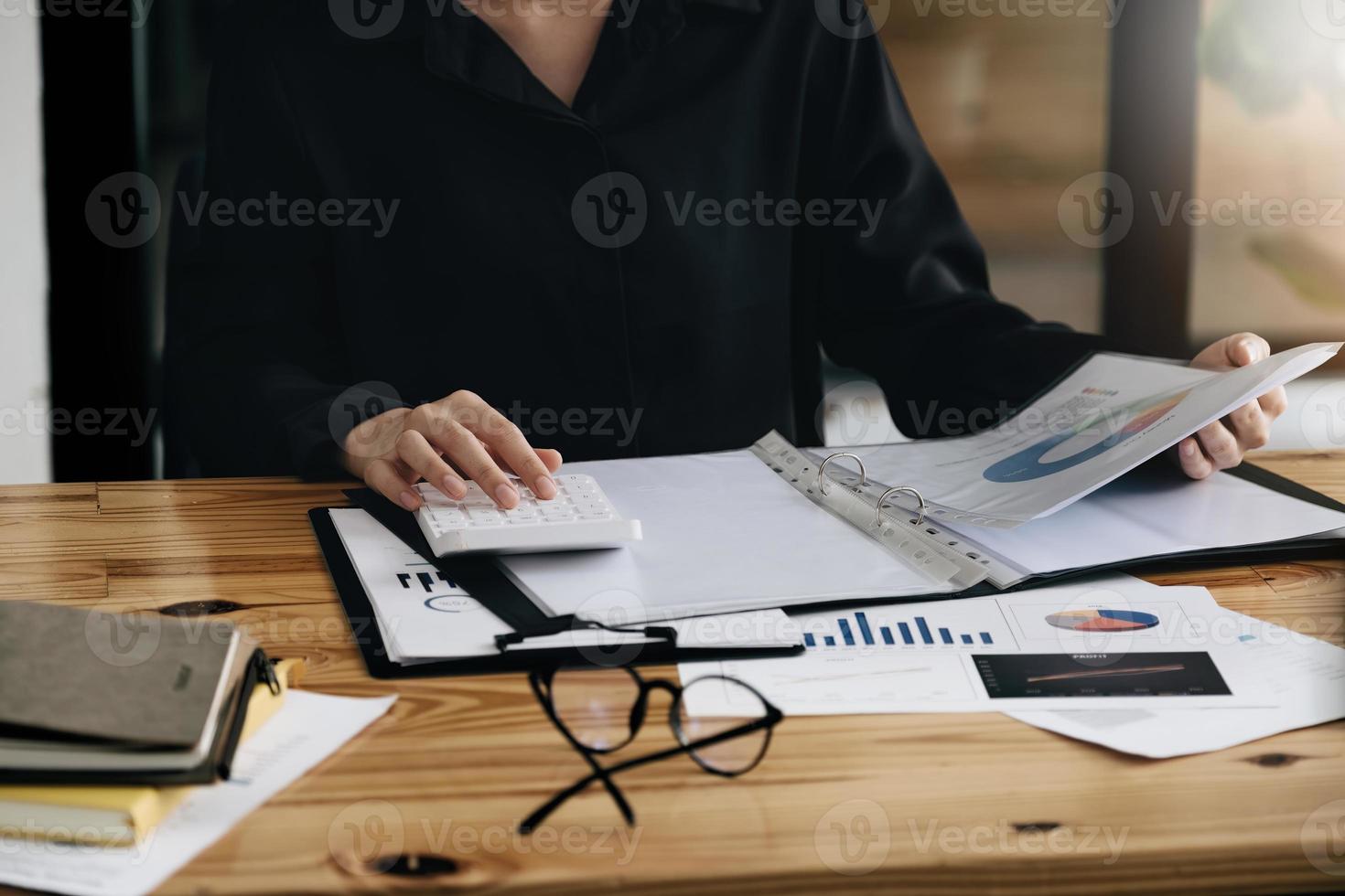 businesswoman working on desk office with using a calculator to calculate the numbers, finance accounting concept. photo